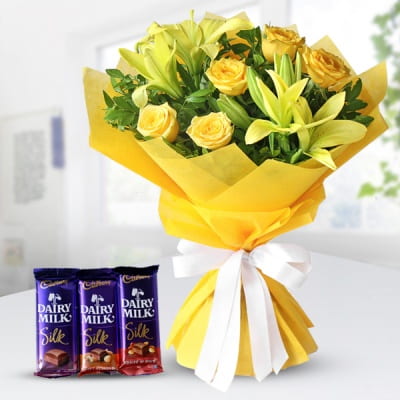 Bouquet of 2 yellow lilies and 6 yellow roses bundled together in a yellow tissue wrapping & 3 Dairy Milk Silk Yellow Dairy Milk Combo
