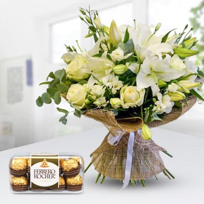 Bouquet of 5 White Roses, 3 stems of Lilies and 3 stems of White estumas and white fillers in nice wrapping along with 16 pcs Ferrero Roche Whitish Combo